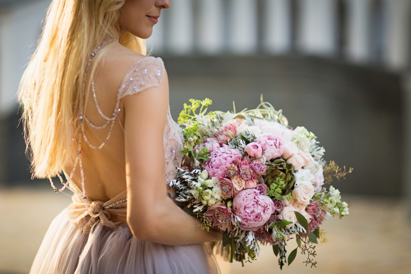 Portrait of an elegant unrecognizable woman wearing grey wedding dress and posing in the street